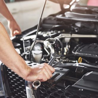 Close up hands of unrecognizable mechanic doing car service and maintenance.